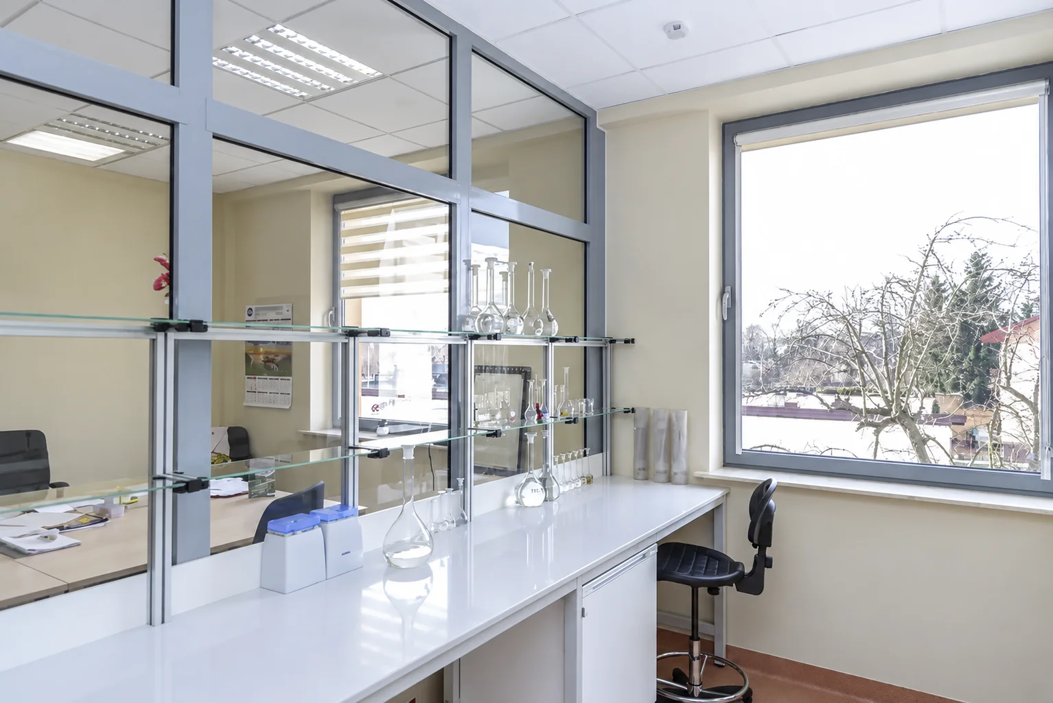 Sanitary and Epidemiological Station in Radom: white worktop by the window, glass shelves with glassware and a stool