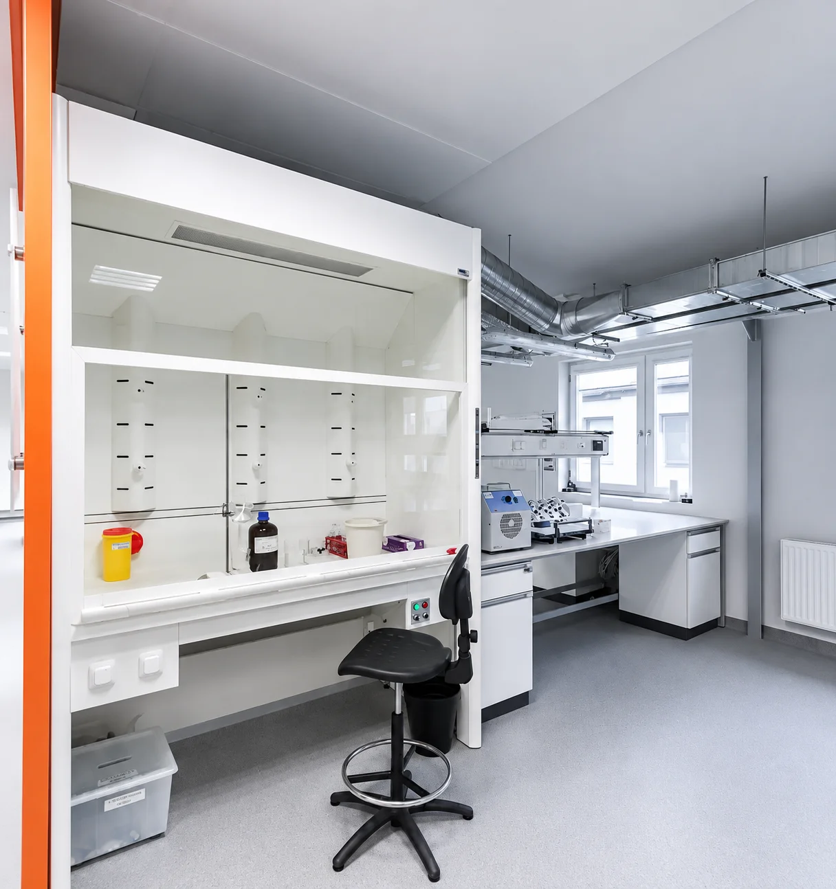 Pharmaceutical laboratory in Warsaw: open fume hood, a bench with instruments and a laboratory chair
