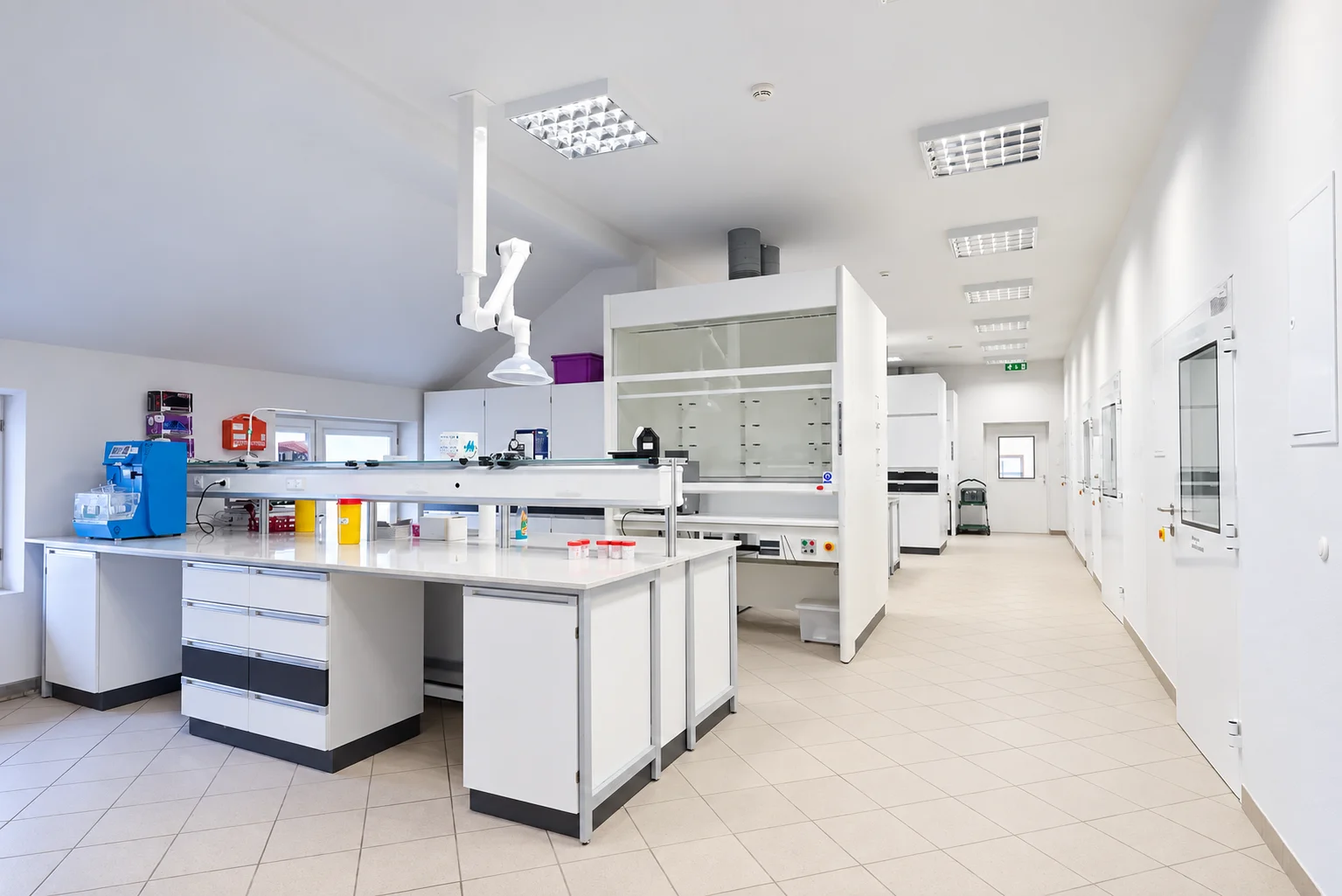 Laboratory with islands, fume hoods and an extraction arm suspended from the ceiling